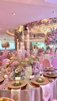 a dining room with tables and chairs covered in pink linens, gold trimmings and floral centerpieces