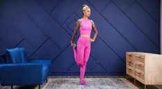 a woman standing in front of a blue couch wearing pink leggings and sports bra