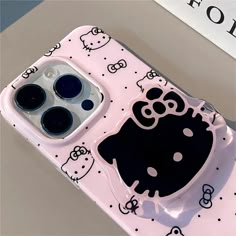 an iphone case with hello kitty design on the front and back sides, sitting on top of a table