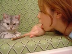 a woman with red hair is petting a cat on the arm of a green couch