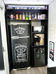 a black refrigerator freezer sitting inside of a kitchen next to a shelf filled with bottles