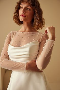 a woman in a white dress is posing for the camera with her arms folded up