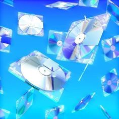 several cds are flying in the air with blue background and clear glass blocks around them