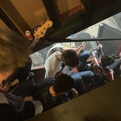 a group of people sitting on top of a train next to each other with guitars