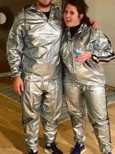 a man and woman dressed in shiny silver outfits standing next to each other on a wooden floor