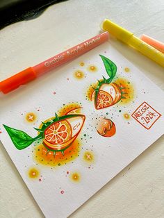 two oranges with green leaves on them are drawn in watercolor and next to a marker