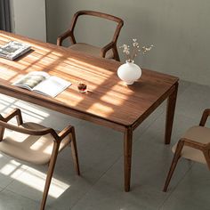 a wooden table with two chairs and a vase on top of it next to a window