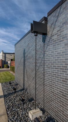 a brick wall next to a graveled area with rocks on the ground and grass behind it