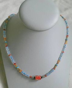 Red/orange bicone crystal beads, blue seed beads, brown seed beads, and a speckled red glass bead in the middle. Toggle clasp. Measures 19.5 inches long end to end. Orange Beaded Necklaces With Czech Glass, Orange Beaded Glass Necklaces, Orange Glass Beaded Necklace With Colorful Beads, Orange Czech Glass Beaded Necklaces, Orange Czech Glass Beaded Necklace, Adjustable Orange Beaded Necklaces With Heart Beads, Adjustable Orange Beaded Necklace With Heart Beads, Handmade Orange Beaded Necklaces With Czech Glass, Handmade Orange Czech Glass Beaded Necklaces