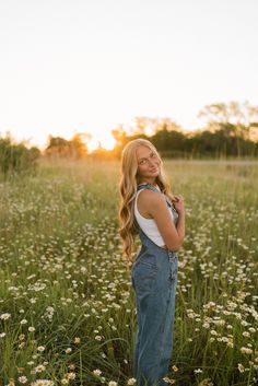 a woman standing in the middle of a field with daisies