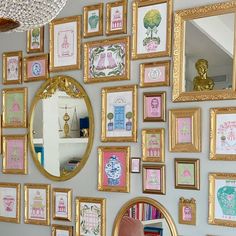 there are many framed pictures on the wall with gold frames and a pink chair in front of it