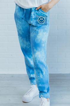 a woman wearing blue tie dye sweatpants with an eye on the side and white sneakers