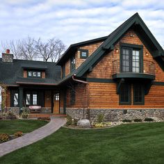 a large wooden house sitting on top of a lush green field