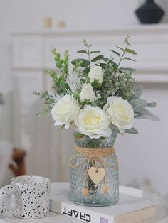 a vase filled with white flowers sitting on top of a table next to a book