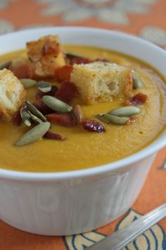 a white bowl filled with soup and croutons on top of an orange table cloth