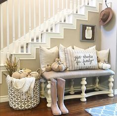 there is a white bench with pillows and boots on it in front of the stairs