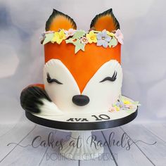 a cake that is shaped like a fox with flowers on it's head and ears