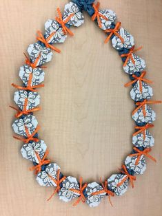 an orange and blue necklace with flowers on the front is made out of paper beads