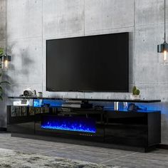 an entertainment center with a large television and blue flames on the bottom shelf, in front of a concrete wall