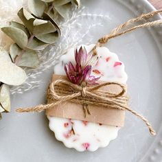 a white plate topped with a piece of wax next to a plant and twine