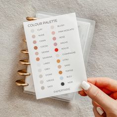 a person holding a paper with some sort of color swatches on it next to gold rings