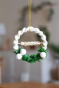 an ornament hanging from a string with the word mom spelled in white beads