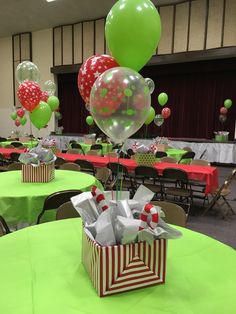 balloons and gift boxes are on the tables at a party with green tablecloths