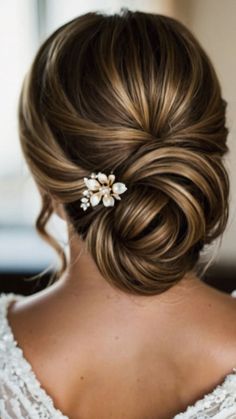 a woman wearing a wedding hair comb with flowers on it's side, looking down at the back of her head