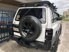 a white jeep parked in front of a gate