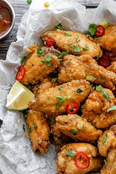 chicken wings with chili peppers and cilantro on parchment paper next to dipping sauce