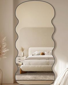 a bedroom with a large mirror reflecting the bed's headboard and foot board