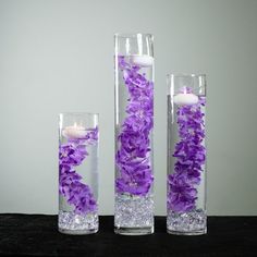 three vases filled with water and purple flowers