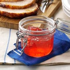 a glass jar filled with jam next to sliced meat