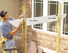 a man is working on a sign in front of a house that has been built