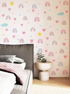 a bed sitting next to a wall with hearts and rainbows on it