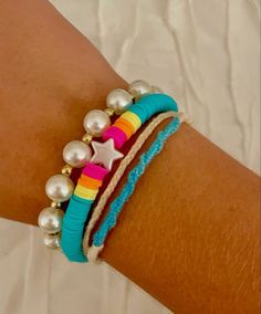 a close up of a person's arm wearing bracelets with pearls and beads