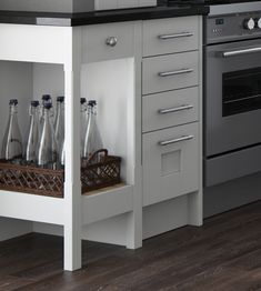 a kitchen with an oven, dishwasher and bottles in the cabinet door drawer