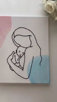 a drawing of a woman holding a baby in her arms on a white surface with flowers