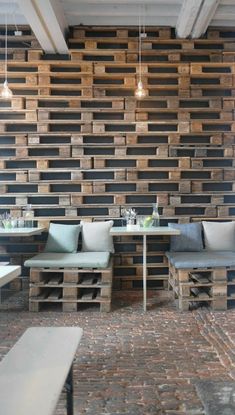 an empty restaurant with wooden pallets on the wall and tables in front of them