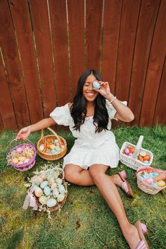 a woman sitting on the grass with some baskets and eggs in front of her face