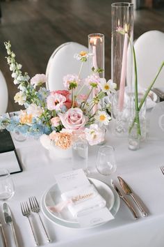 the table is set with flowers, candles and place settings for an elegant wedding reception