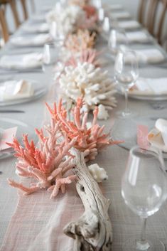 the table is set with corals and place settings for dinner guests to eat at