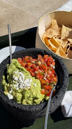 a bowl filled with guacamole and tortilla chips on top of a table