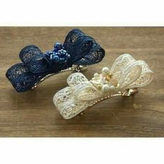 two hair clips with lace and pearls on them sitting on a table next to each other