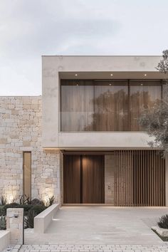 the front entrance to a modern house with large windows and wooden shutters on both sides