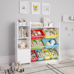 a white book shelf filled with lots of colorful bins next to a stuffed animal