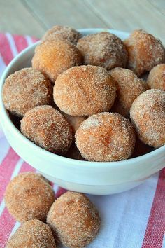 a bowl filled with sugar covered donuts on top of a red and white towel