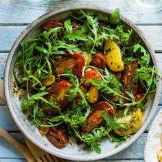 a white bowl filled with lots of veggies on top of a wooden table