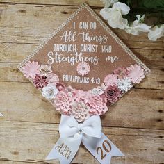 a graduation cap decorated with flowers and ribbon on top of a wooden table next to scissors