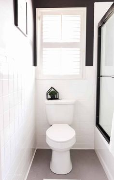 a white toilet sitting in a bathroom next to a window